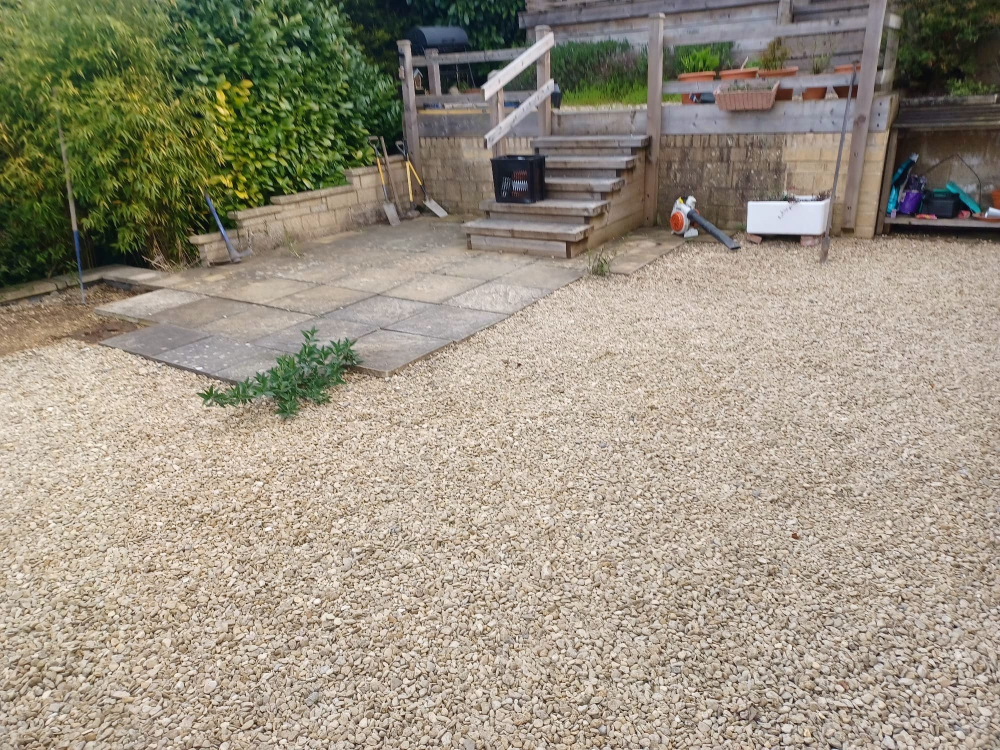 Bare gravel and concrete patio area before works